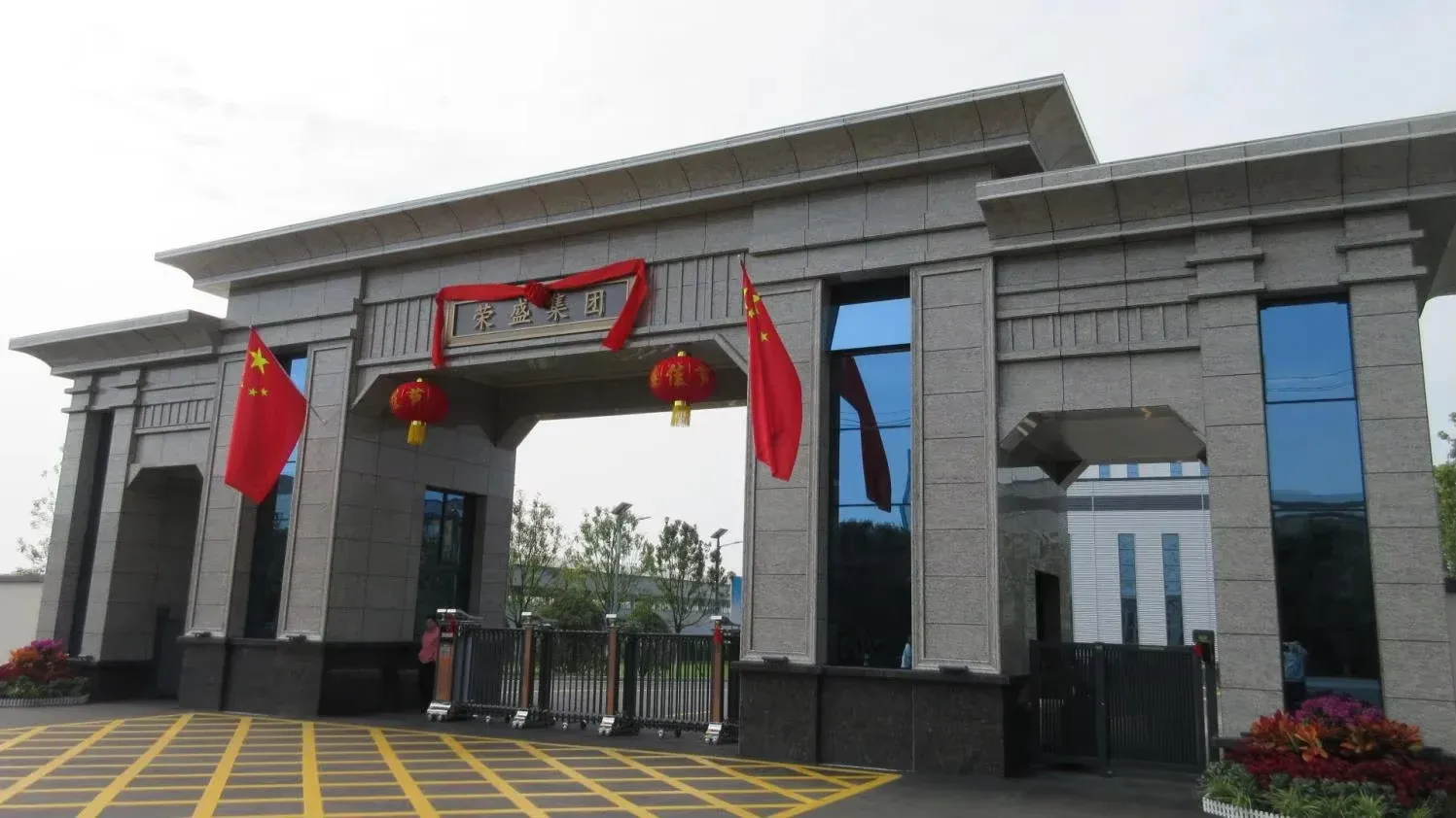 Stone entrance gate of the RISING REFRACTORY Group with the group name in Chinese, red lanterns and national flags